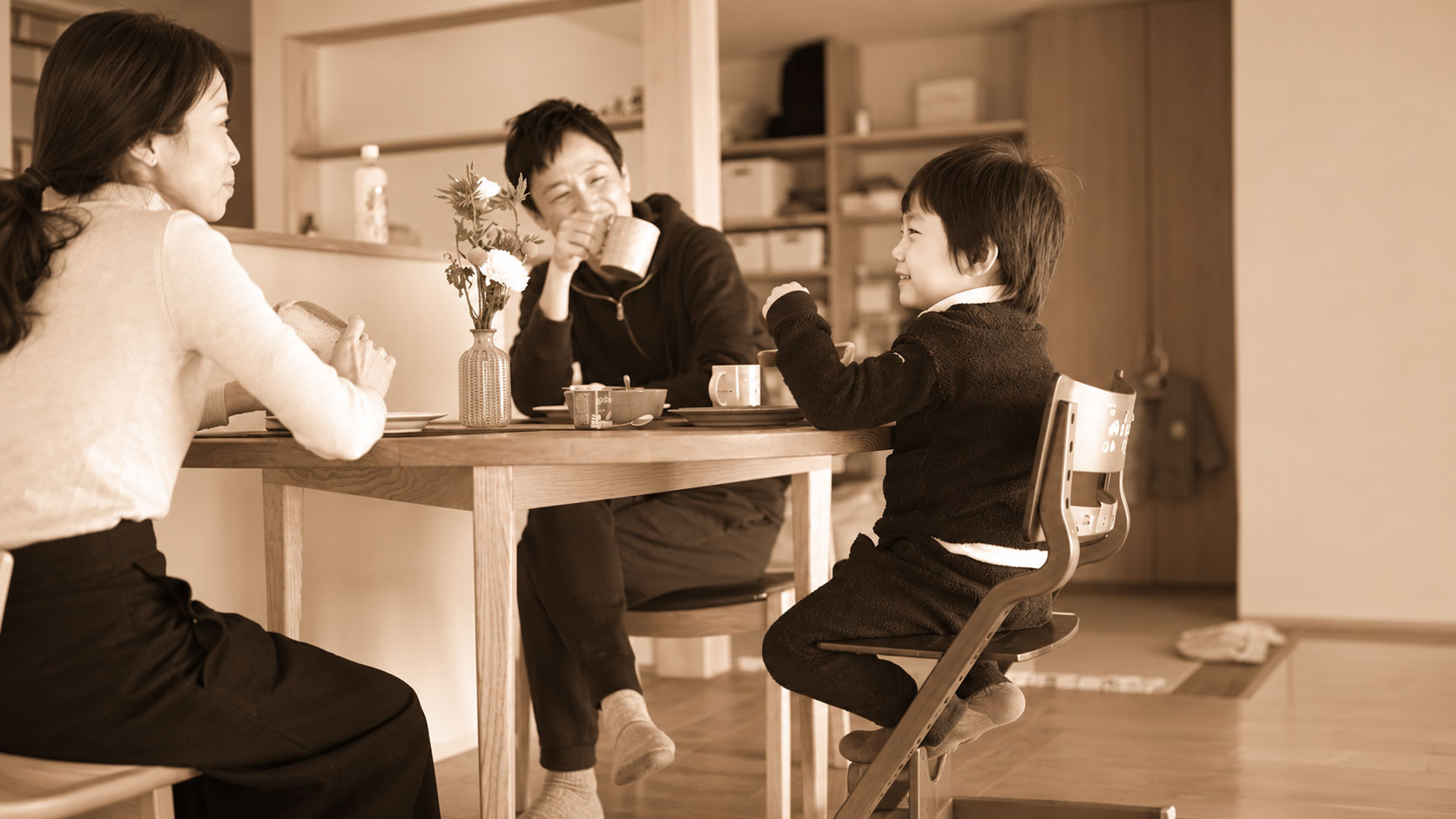 Family of three at a wooden table sharing breakfast in a cozy kitchen.