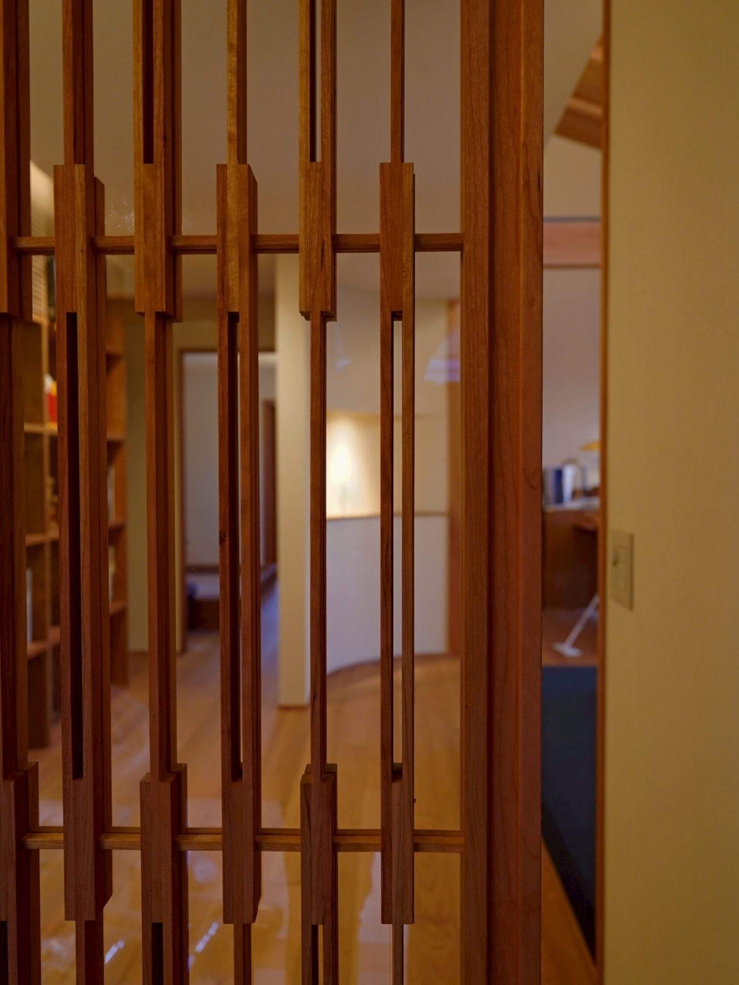 Wooden vertical slats form a decorative room divider, with a warmly lit interior visible beyond.
